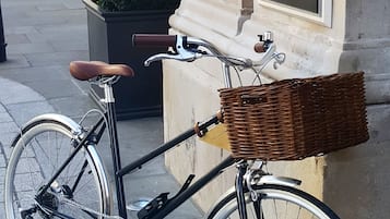 Ein Fahrrad mit einem Korbrad am Vorderbau, abgestellt auf einem Bürgersteig.