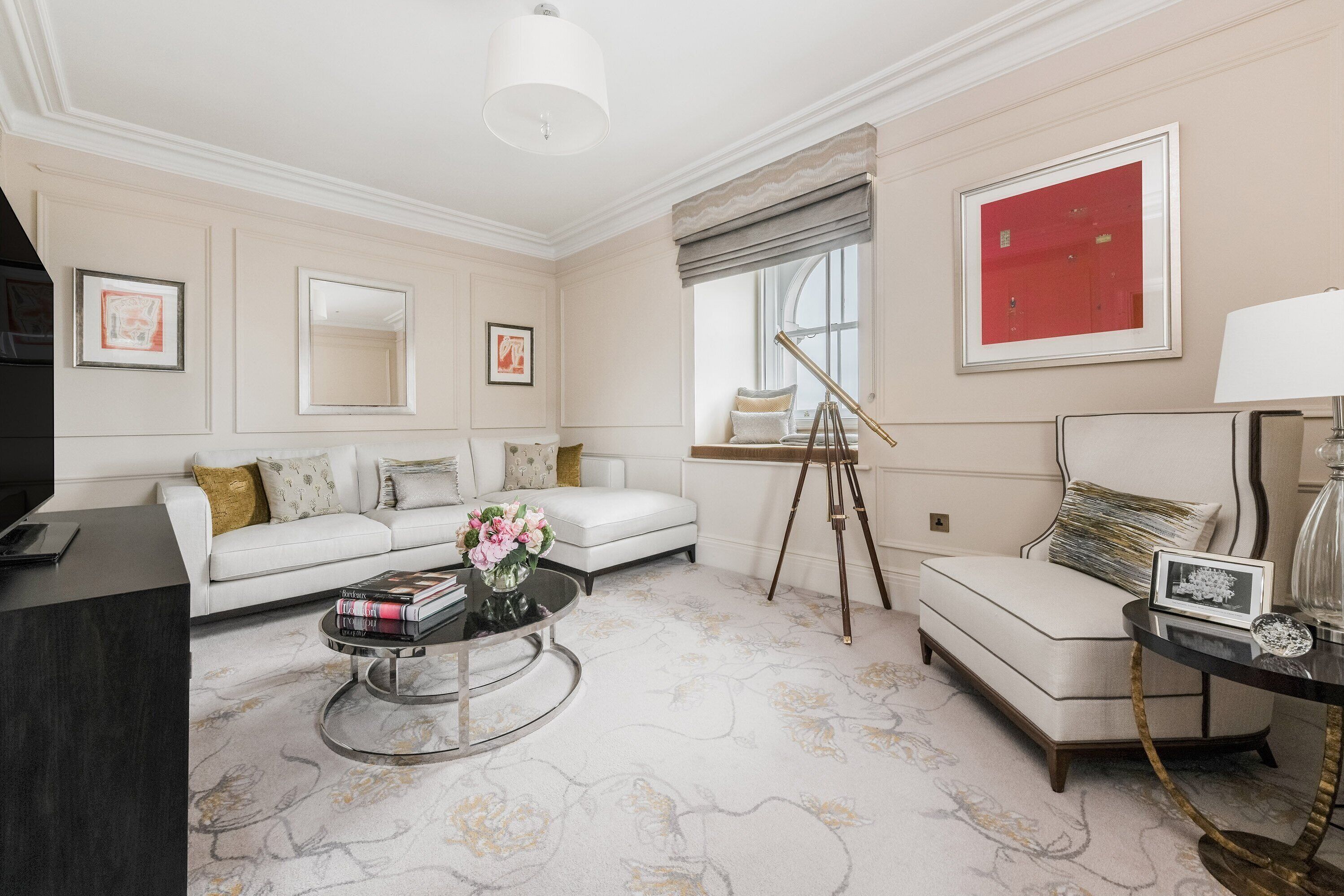 A modern living room with a white sofa, a coffee table, and a painting on the wall.