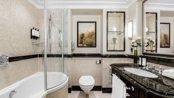A modern bathroom with a glass-enclosed shower, a white toilet, and two sinks with dark countertops.