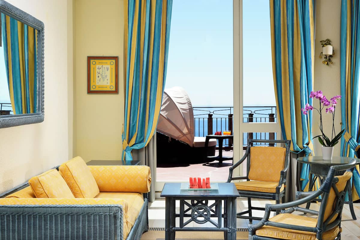 A balcony with wicker furniture, a table with drinks, and a potted plant.