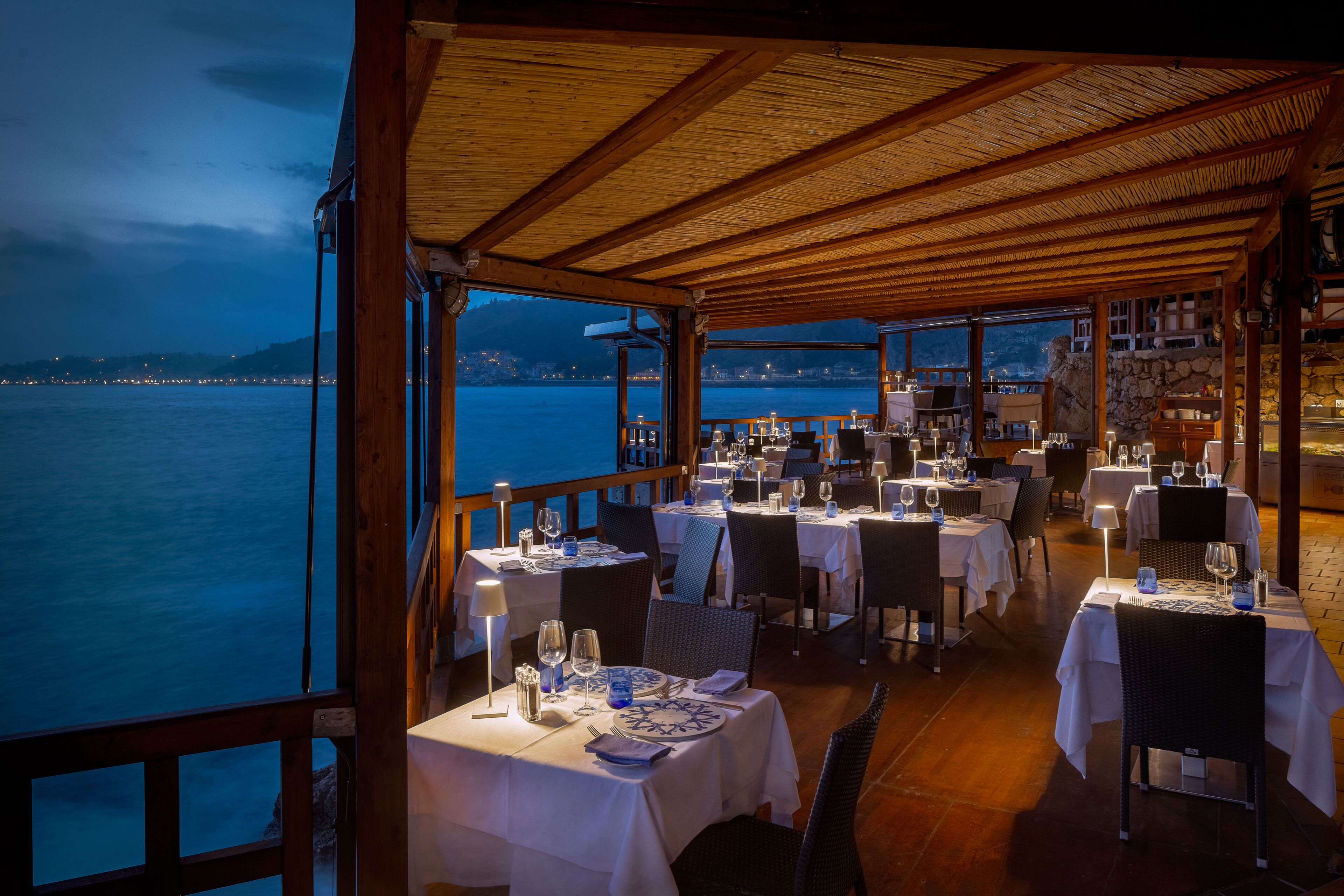 Restaurante con mesas dispuestas para comer, con vista a un cuerpo de agua.