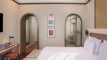 Une chambre d’hôtel avec un lit, un bureau, une chaise et deux tableaux encadrés au mur.