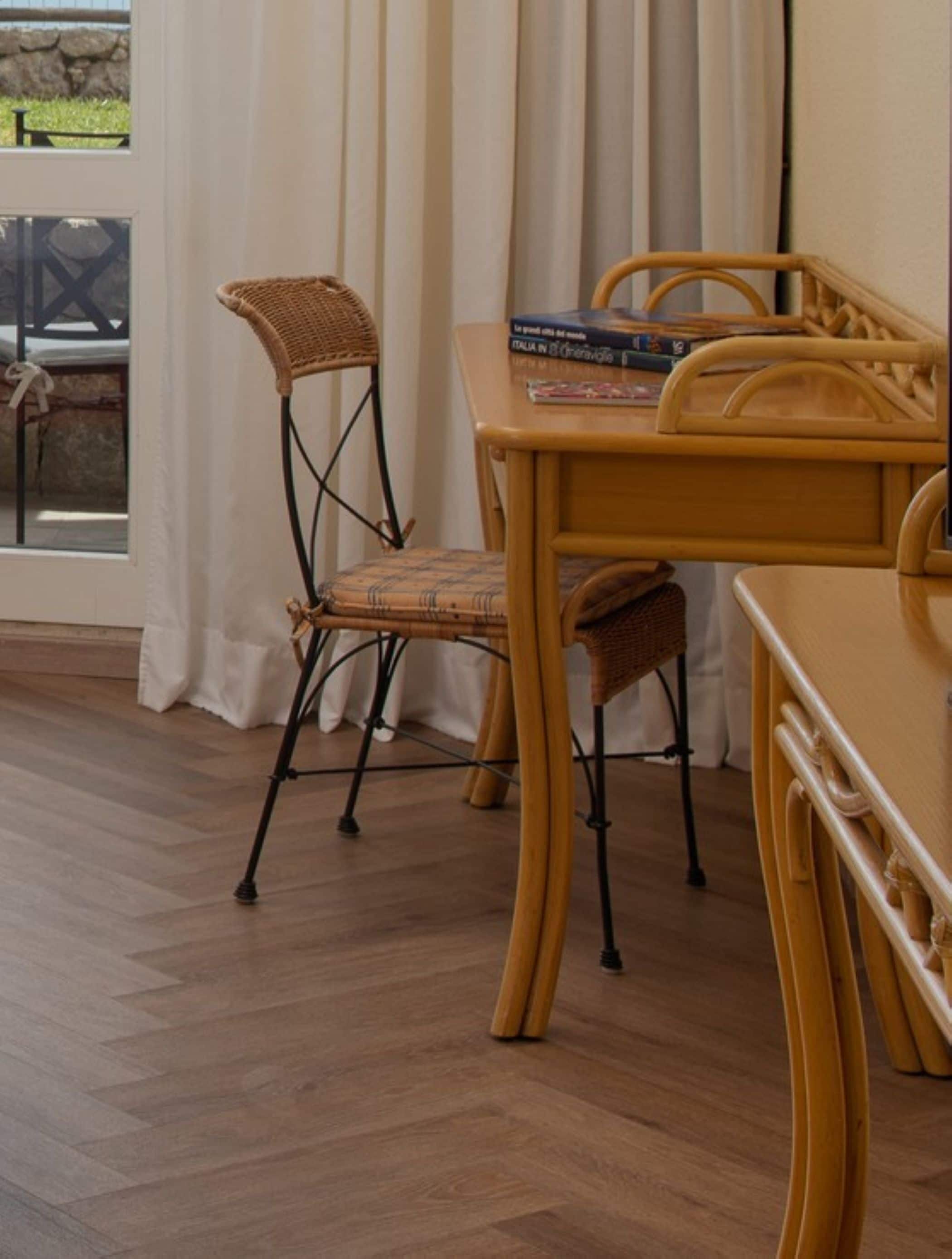 A dining area with wicker chairs, a wooden table, and a view through a glass door.
