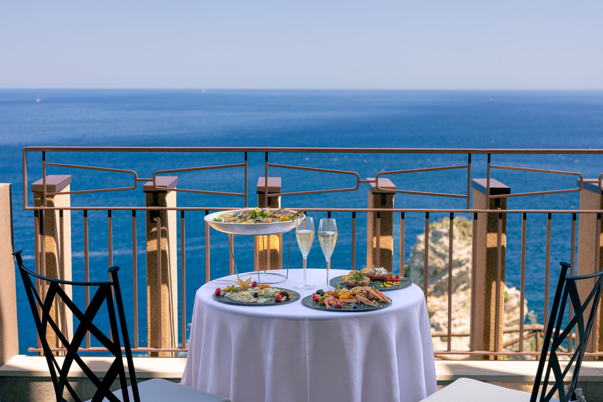 A table set with a variety of dishes and glasses, overlooking a scenic ocean view.