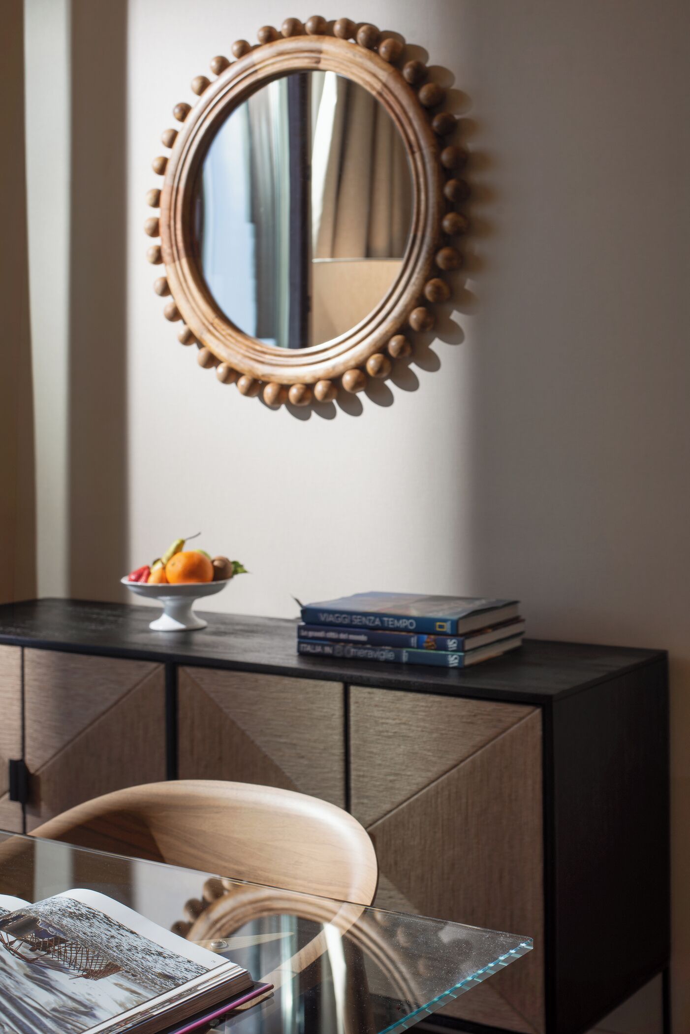 Een kamer met een spiegel, een fruitschaal, boeken en een stoel.