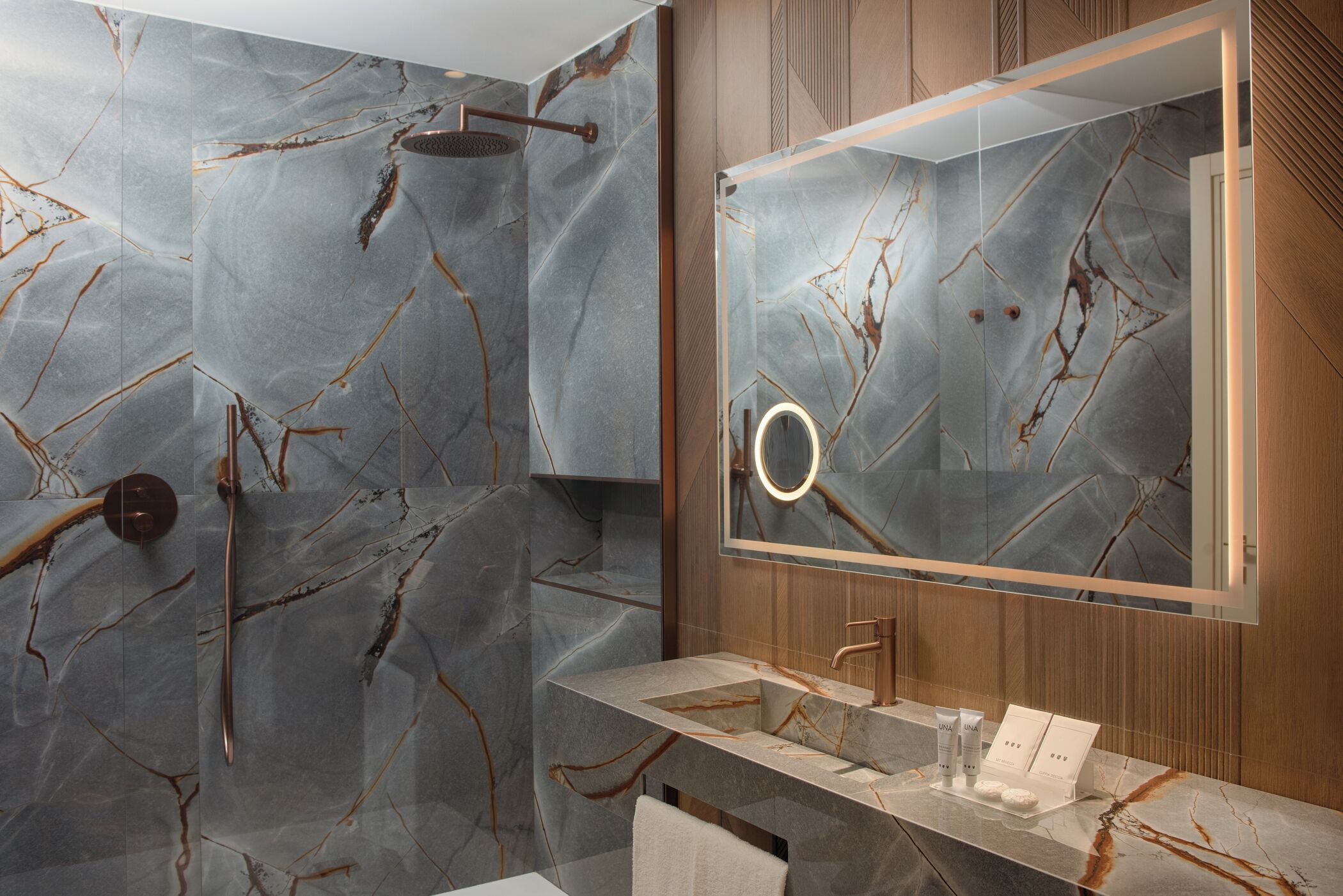 A bathroom with marble walls, a modern sink, and a large mirror.