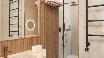 A modern bathroom with a marble vanity, a towel rack, a shower with a handheld showerhead, and a wooden panel wall.