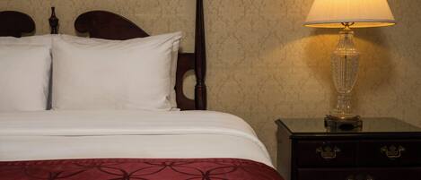 A bed with a headboard, a bedside table with drawers, and a lamp.