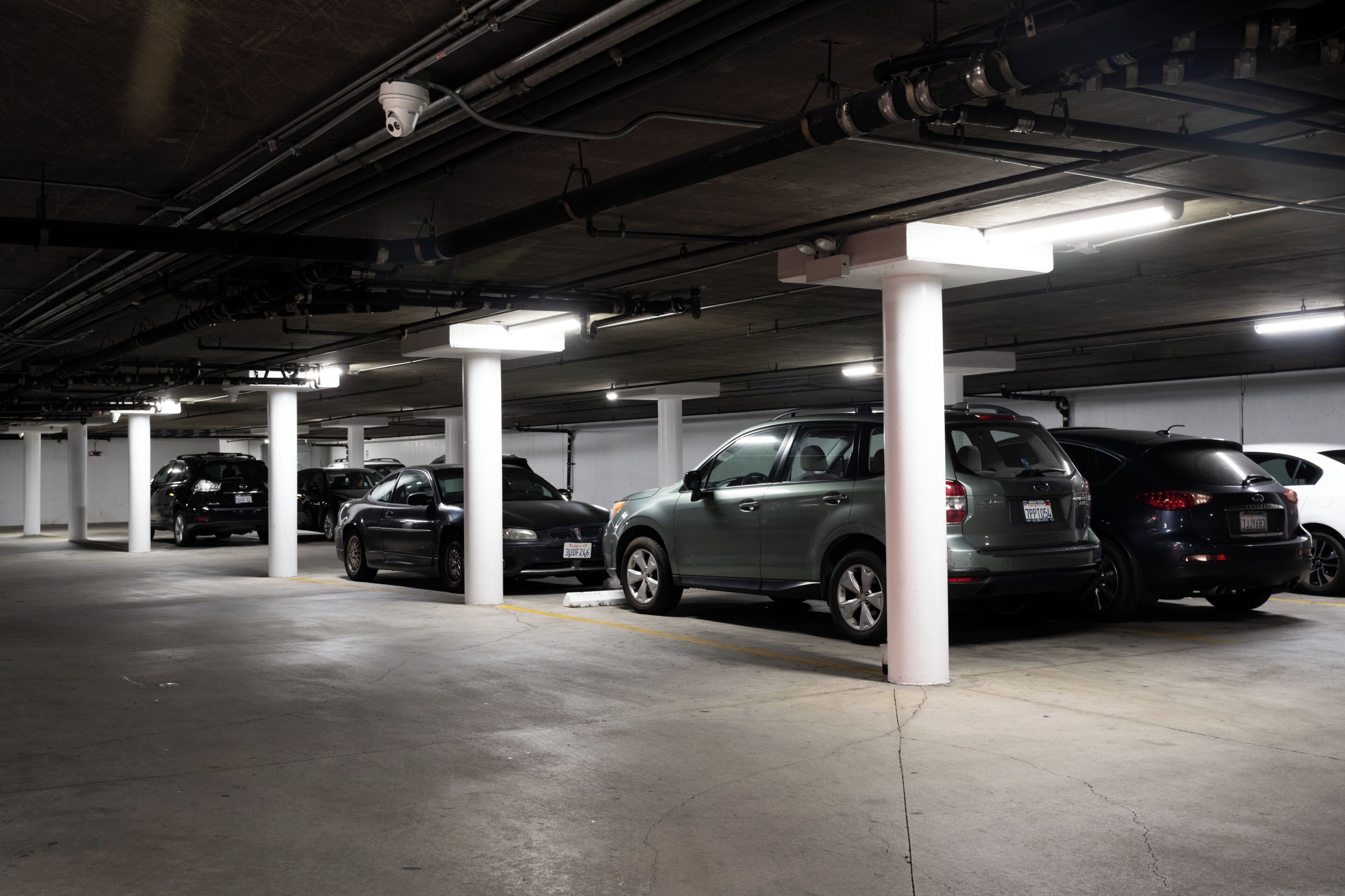Um parque de estacionamento com vários andares, com diversos carros estacionados sob pilares brancos.