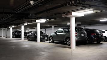 A multi-level parking garage with several cars parked under white pillars.