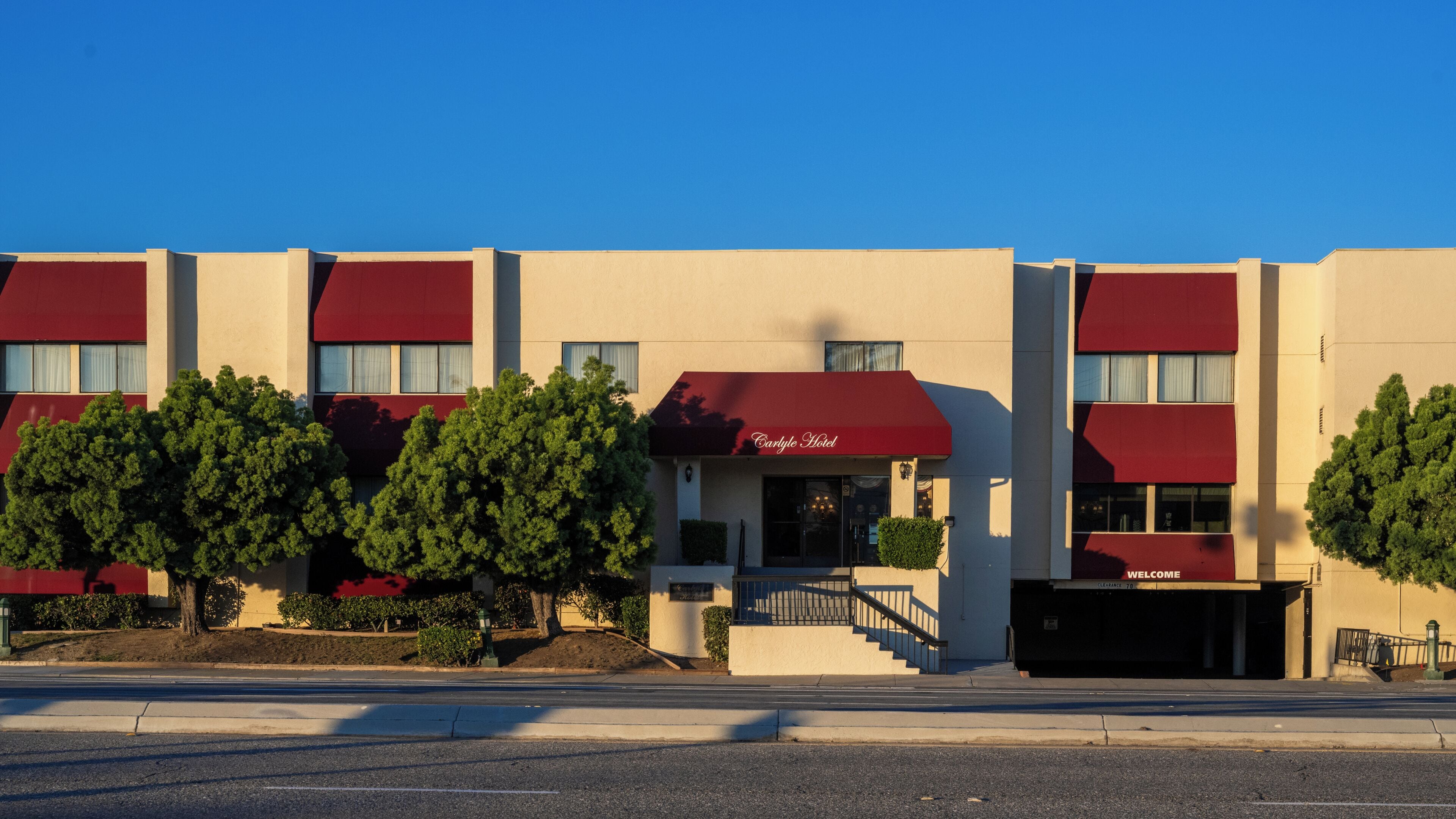 A hotel with a red awning, a clear sky, and a well-maintained lawn.