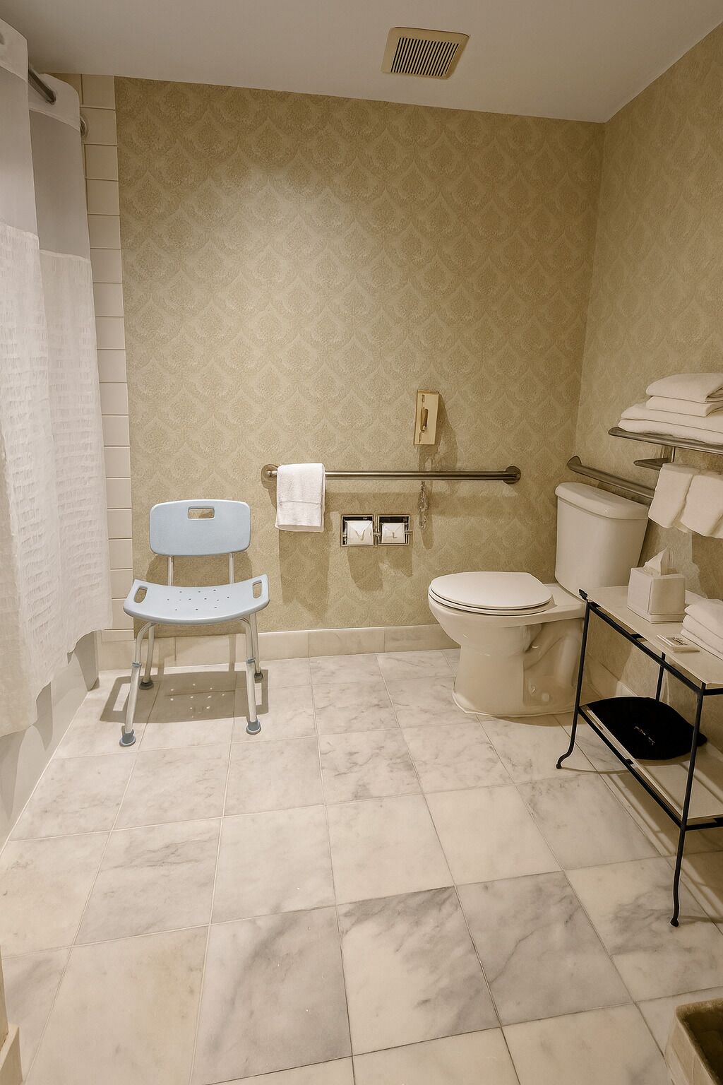 Un baño con inodoro blanco, asiento de ducha blanco, toallero y cubo de basura.