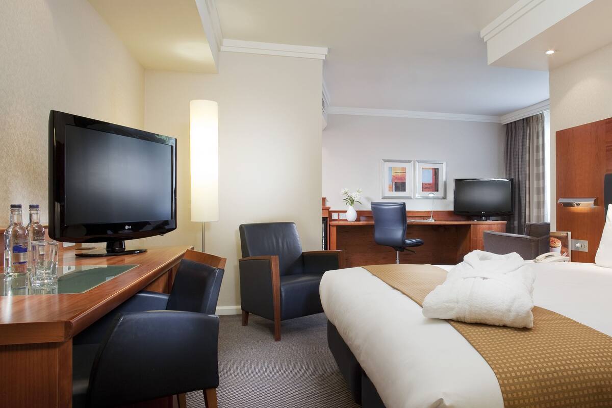 Une chambre d’hôtel comprenant un lit, un bureau avec une télévision, une chaise et une lampe de bureau.