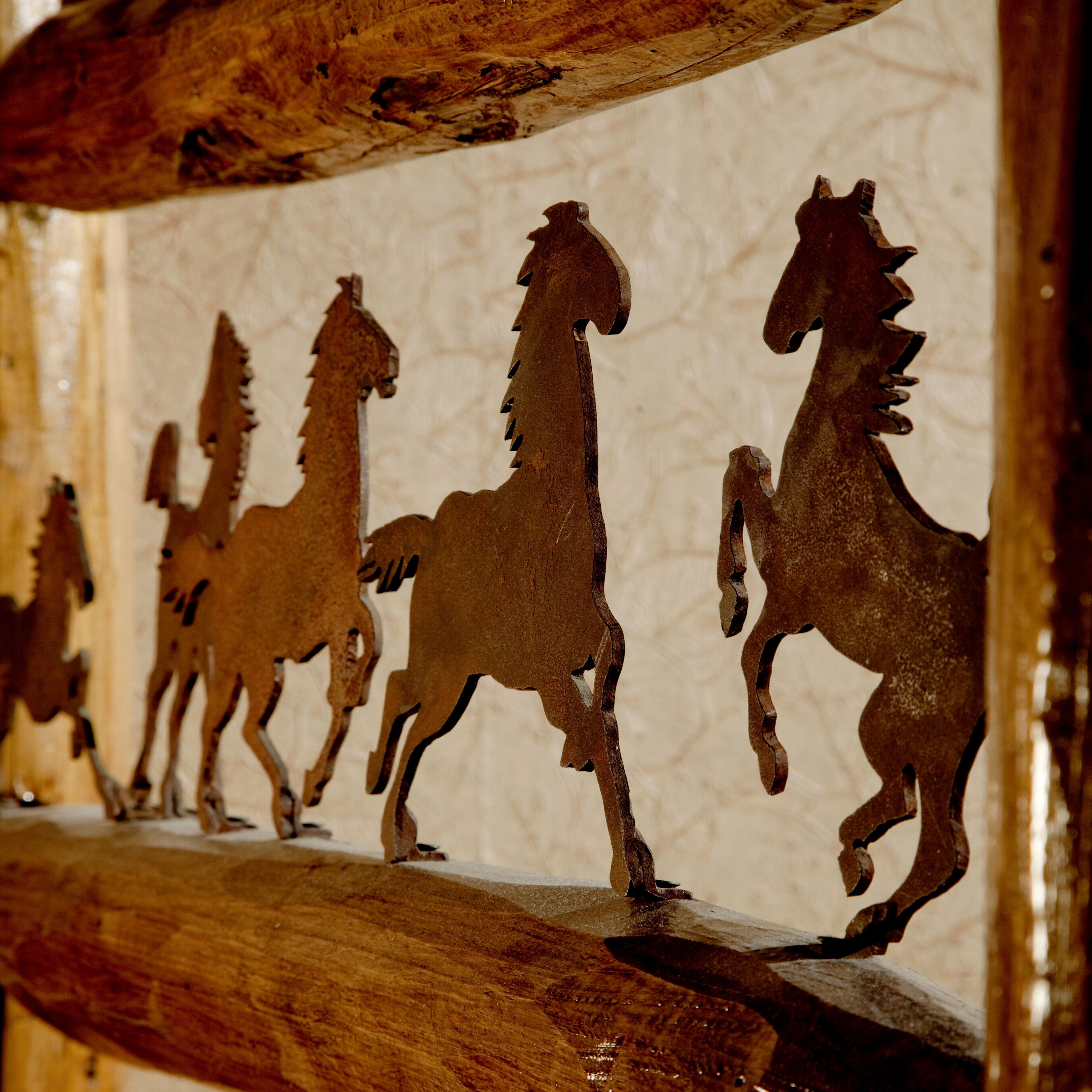 A series of metal horse silhouettes mounted on a wooden structure.