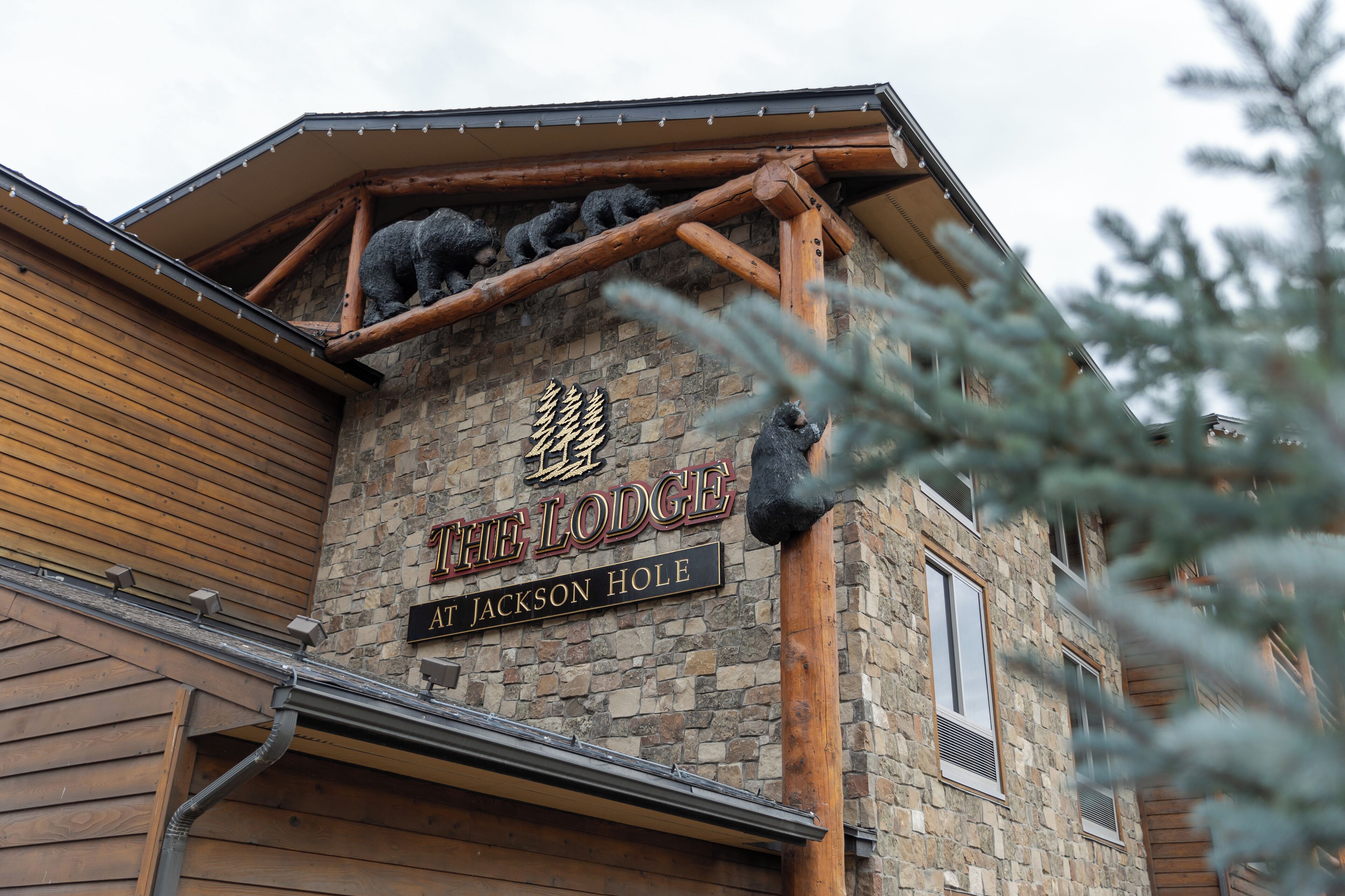 A building with a stone facade and wooden beams, featuring a sign that reads "The Lodge at Jackson Hole."