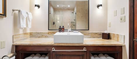 Une salle de bain avec un grand miroir, un lavabo et deux porte-serviettes avec des serviettes.