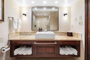 A bathroom with a large mirror, a sink, and two towel racks with towels.