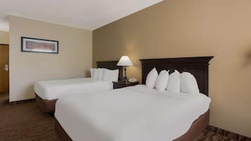 Una habitación de hotel con dos camas, una mesita de noche con lámpara y un cuadro en la pared.