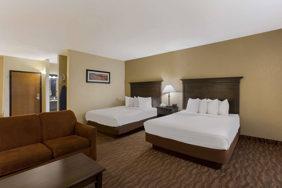 A hotel room with two beds, a sofa, and a small table.