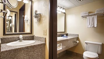 Baño con encimera de granito, lavamanos, espejo, secador de pelo y retrete.