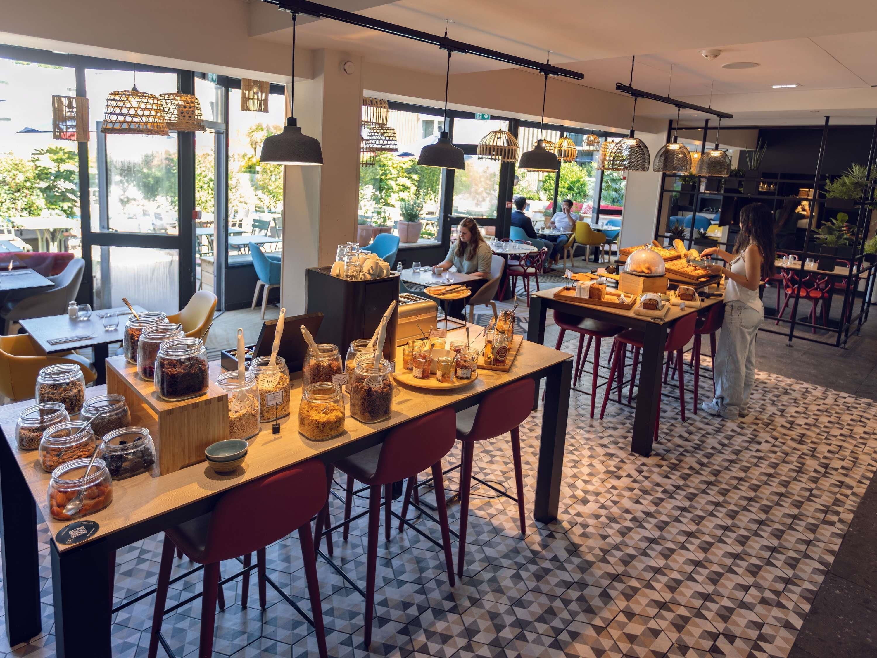 A cafe with tables, chairs, and a variety of food items displayed.