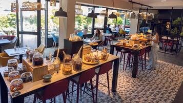 A cafe with tables, chairs, and a variety of food items displayed.