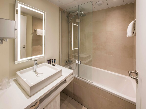 A modern bathroom with a white sink, mirror, and glass-enclosed shower.