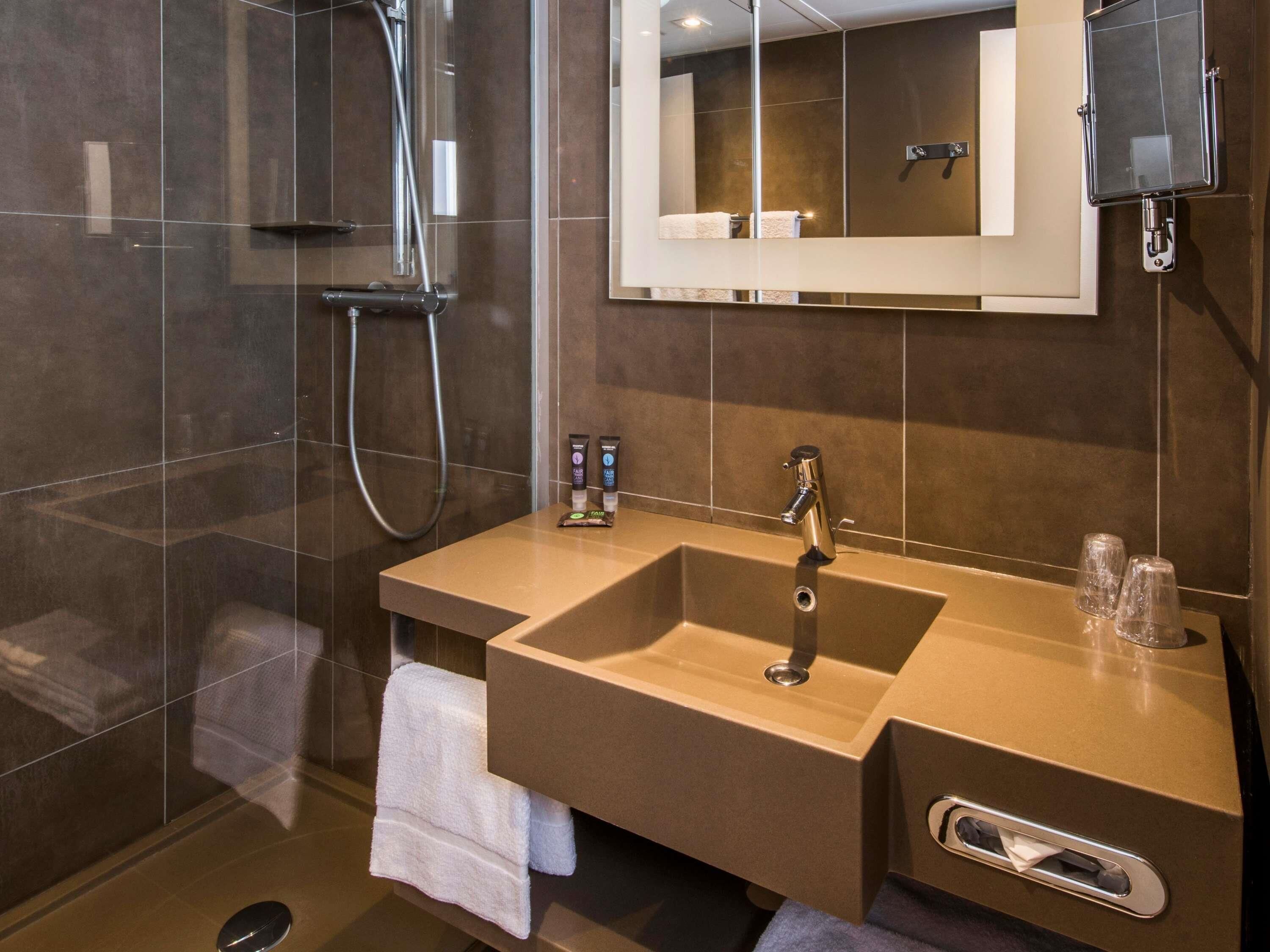 Un bagno moderno con cabina doccia in vetro, lavabo e specchio.