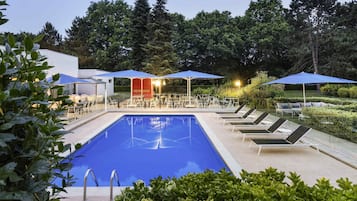 Una piscina al aire libre de temporada, sillones reclinables de piscina