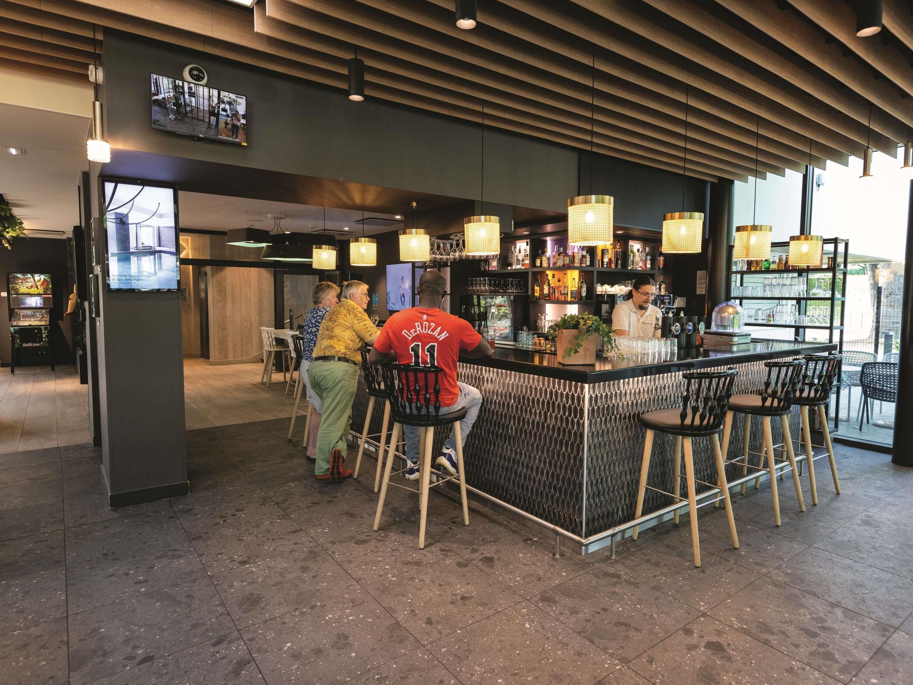 A bar area with a counter, stools, and a television screen.