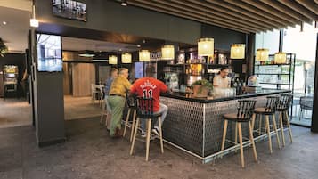 A bar area with a counter, stools, and a television screen.