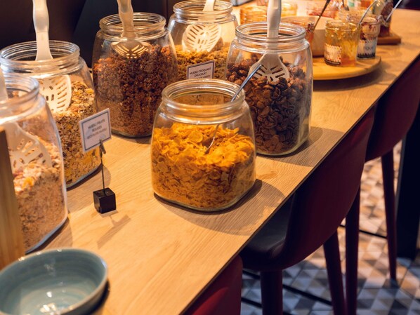 A buffet table with various food items in glass jars, including cereal and granola.