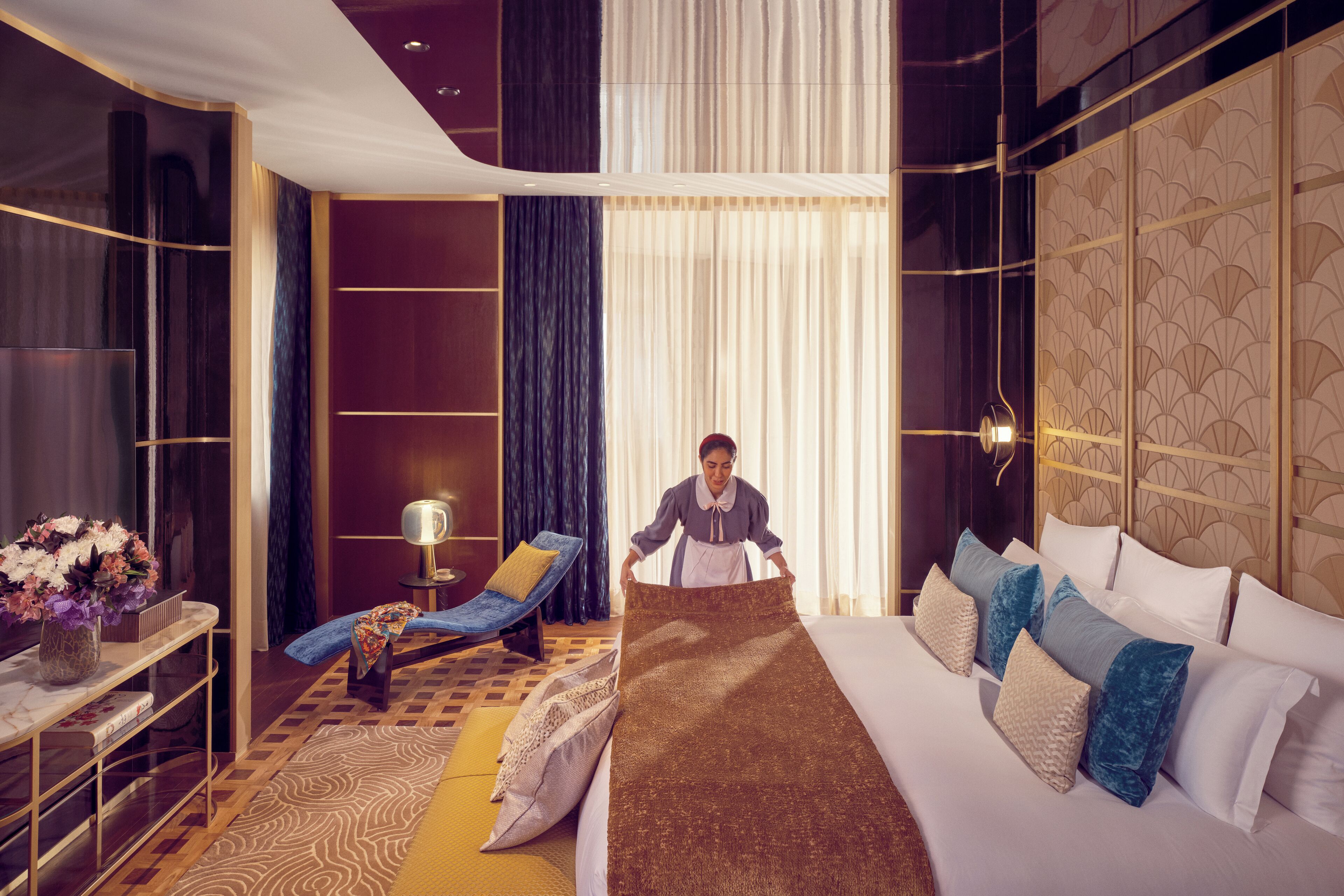 A hotel room with a bed, a sitting area with a chair and a table, and a large window with curtains.