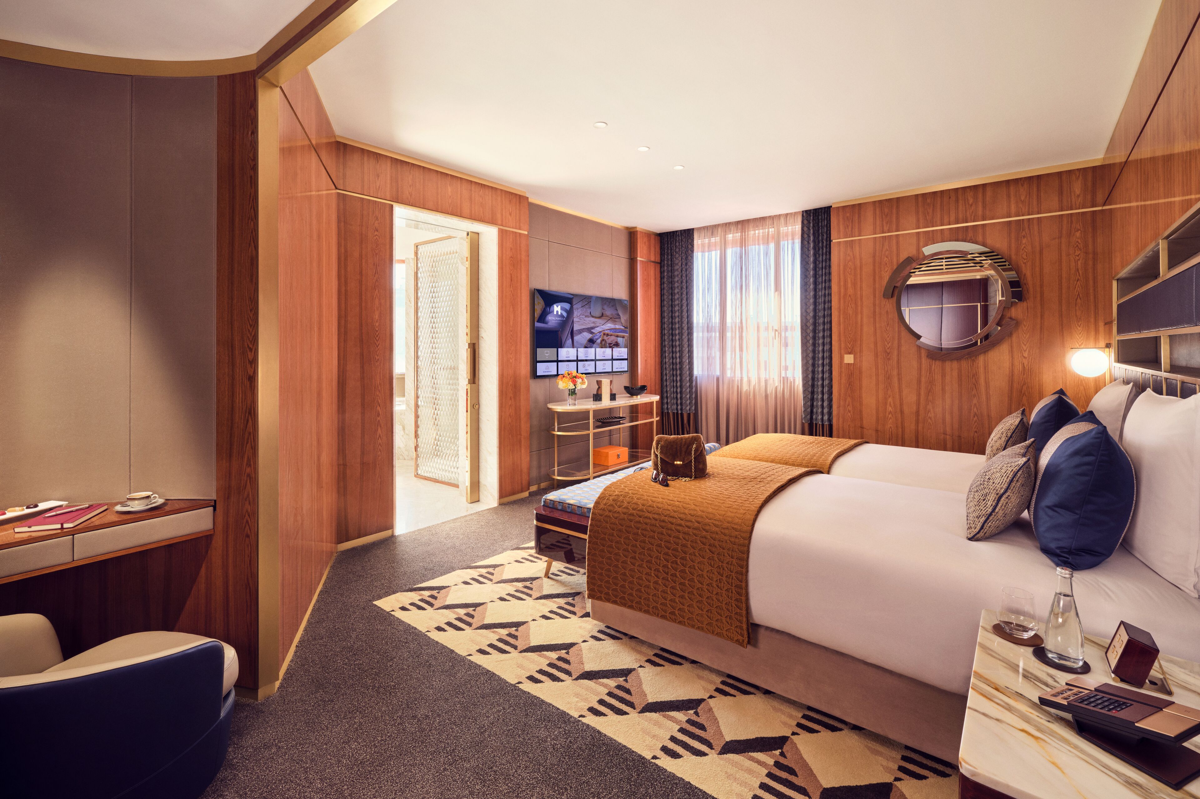 Une chambre d’hôtel avec un lit, un bureau, une chaise, une télévision et une salle de bain visible à travers une porte ouverte.