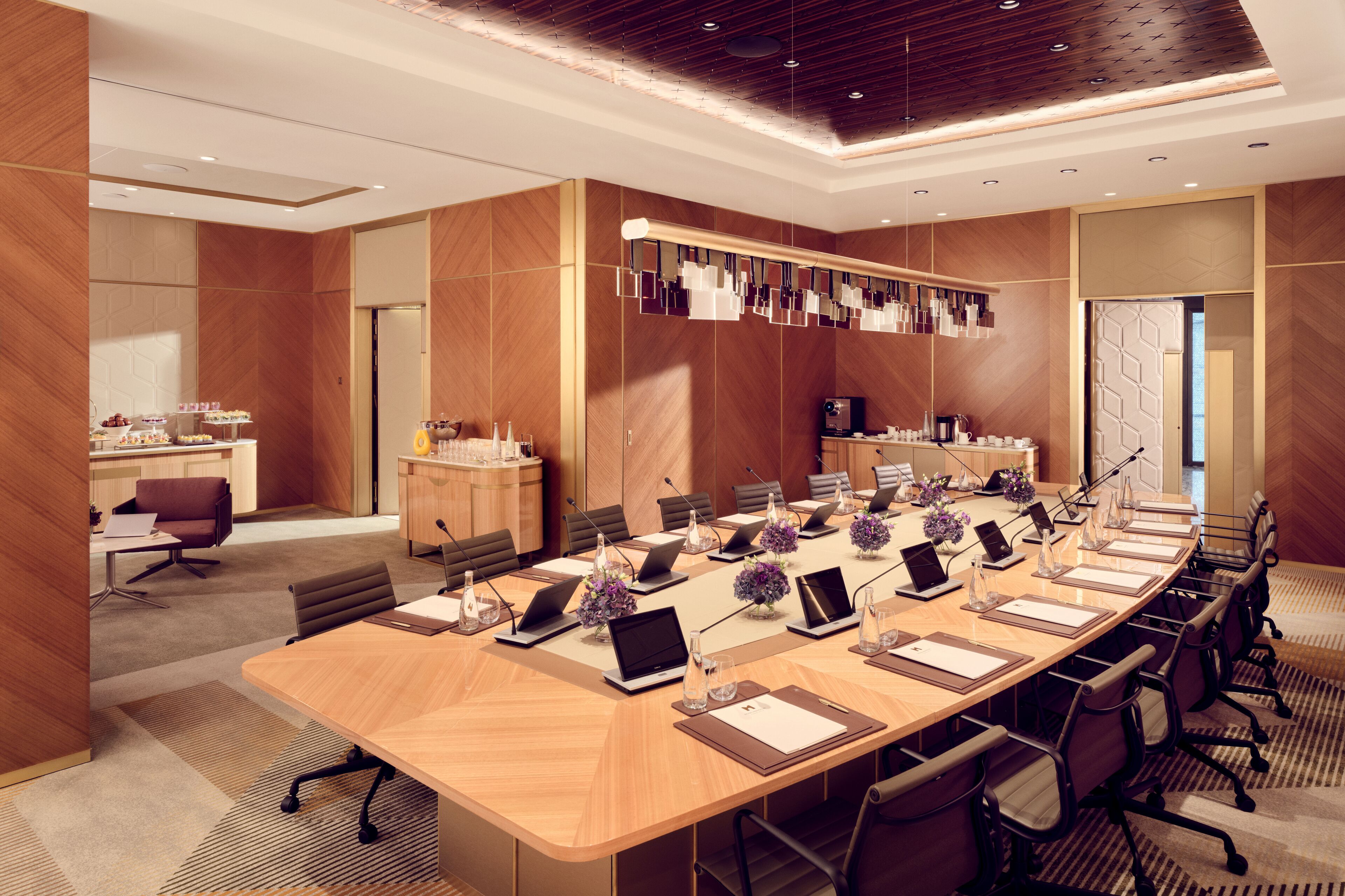 A conference room with a long table, multiple chairs, laptops, and decorative items.