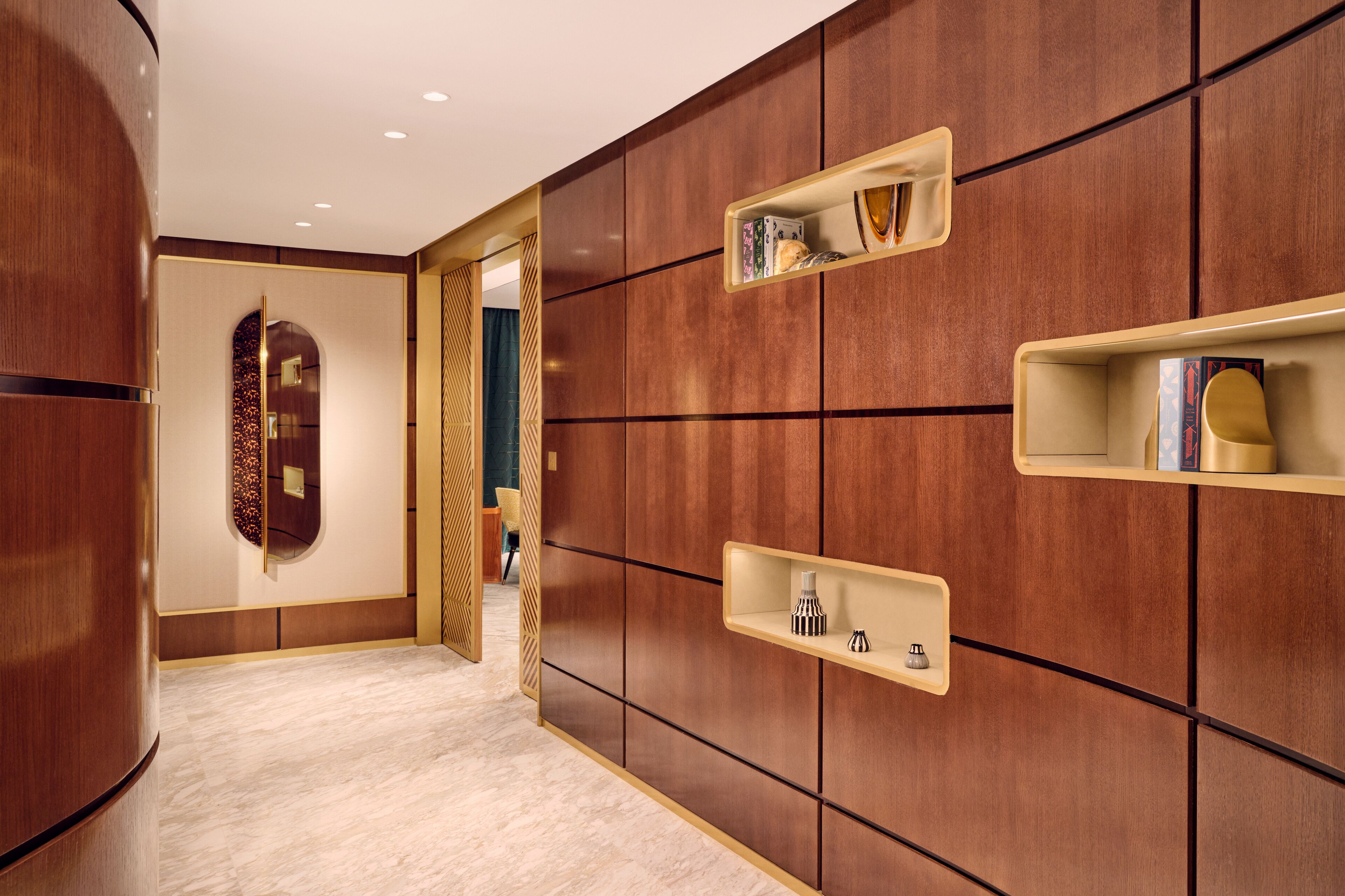 A hallway with wooden paneling, built-in shelves, and a marble floor.