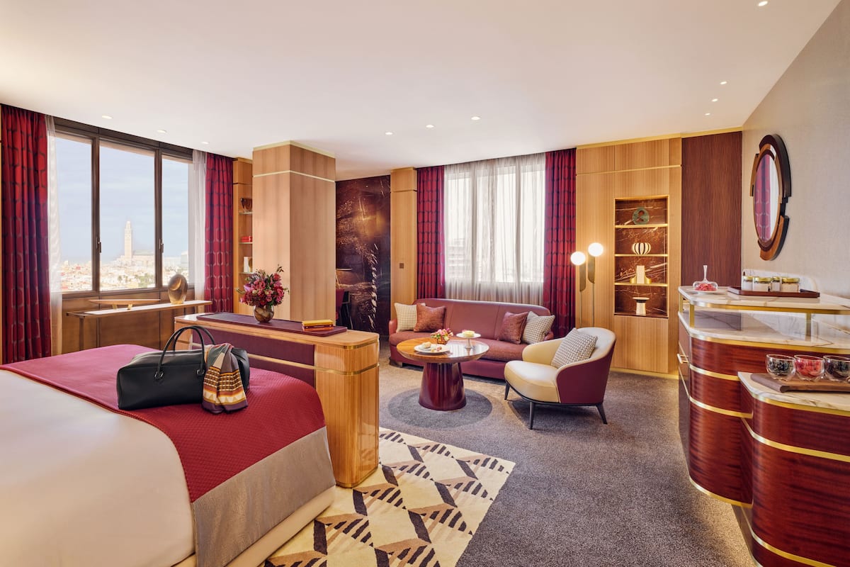A hotel room with a bed, a sofa, a desk, and a dining area.