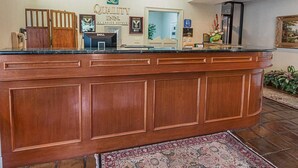 Un comptoir d’accueil d’hôtel avec un comptoir en bois, un ordinateur Dell et un panneau indiquant que l’hôtel fait partie du groupe Choice Hotels.