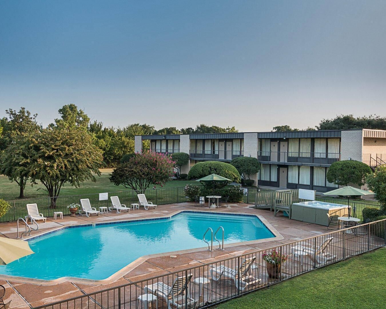 A swimming pool with lounge chairs and a fenced patio area.