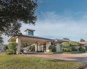 Un hôtel Quality Inn doté d’une station-service couverte, d’une façade en briques et d’un aménagement paysager bien entretenu.