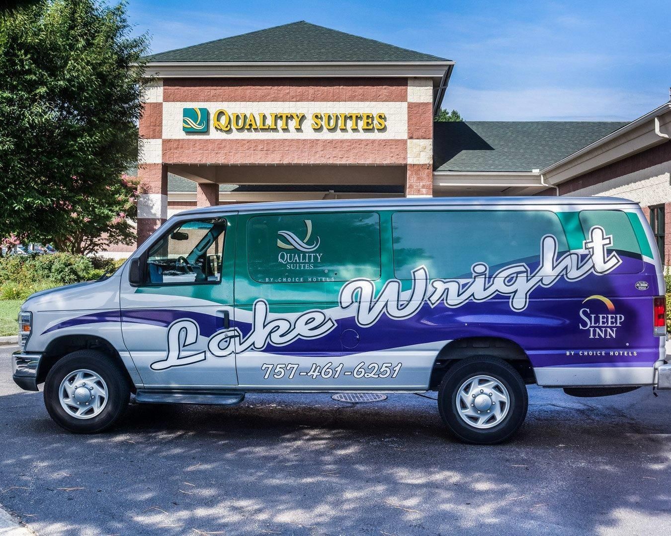 Un fourgon arborant les logos « Lake Wright » et « Quality Suites » est stationné devant un hôtel.