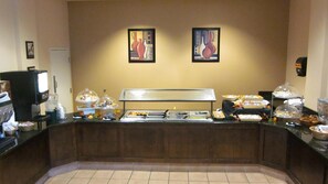 A buffet counter with various food items and a coffee machine. - Quality Suites Lake Wright - Norfolk Airport (Norfolk)