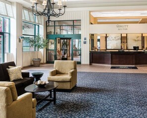 A hotel lobby with a reception desk, seating area, and large windows. - Quality Suites Lake Wright - Norfolk Airport (Norfolk)