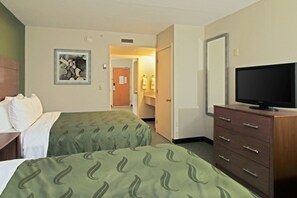 A hotel room with two beds, a television on a dresser, and a bathroom visible through an open door. - Quality Suites Lake Wright - Norfolk Airport (Norfolk)
