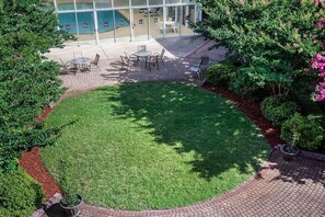 An outdoor patio area with a circular lawn, seating arrangements, and a glass building in the background. - Quality Suites Lake Wright - Norfolk Airport (Norfolk)