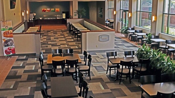 A hotel lobby with a check-in counter, seating area with tables and chairs, and large windows with views. - Quality Suites Lake Wright - Norfolk Airport (Norfolk)