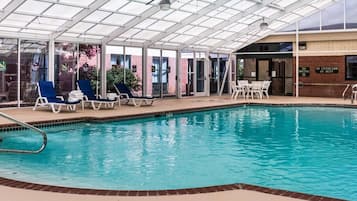An indoor swimming pool with lounge chairs and a covered area.