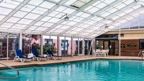 An indoor swimming pool with lounge chairs and a covered area. - Quality Suites Lake Wright - Norfolk Airport (Norfolk)