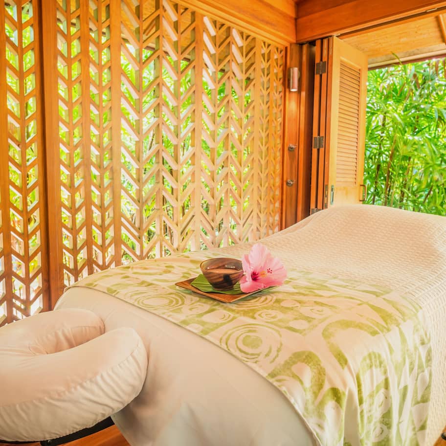 A room with a bed, wooden lattice partition, and a view of greenery.