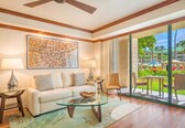 A modern living room with a glass coffee table, a white sofa, and a large window offering a view of a resort.